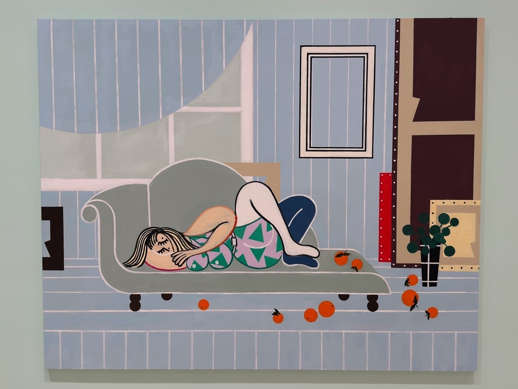 Playful, stylized painting of a reclining woman in a geometric swimsuit on a pale green chaise lounge. Set in a pastel-striped room, the scene includes scattered oranges and abstract picture frames, combining leisure with flat, decorative design.
