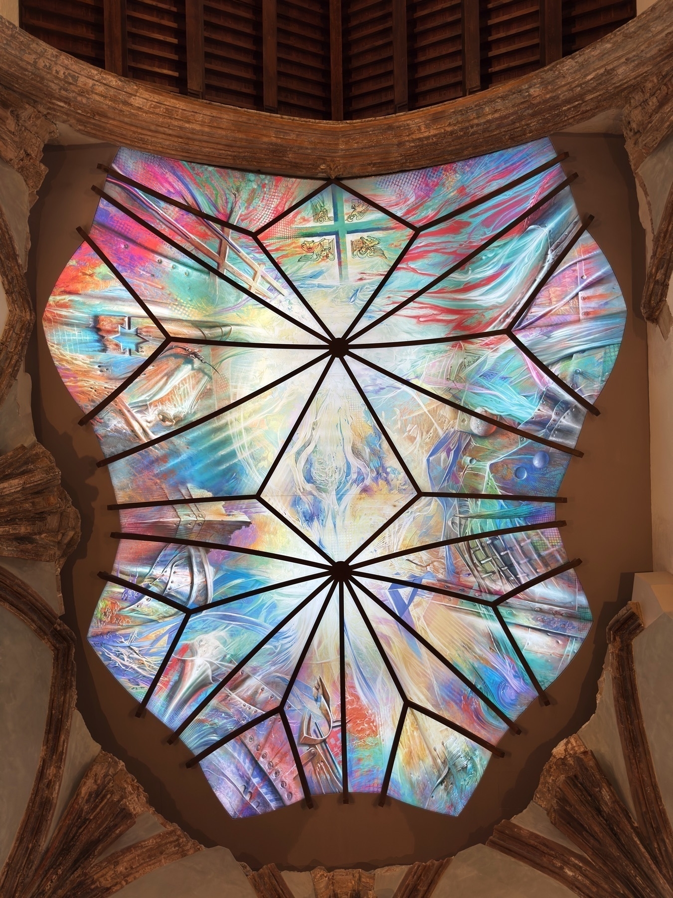 Detailed view of a vivid stained-glass dome ceiling, composed of triangular panels radiating from a central point. The abstract artwork features a mix of bright blues, purples, and reds, creating a celestial effect against the Gothic architecture.