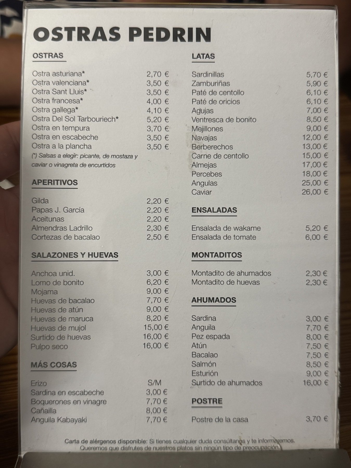 Close-up of the printed menu from Ostras Pedrín, showing a detailed list of oysters, appetizers, preserved and smoked seafood, and other small plates with corresponding prices.