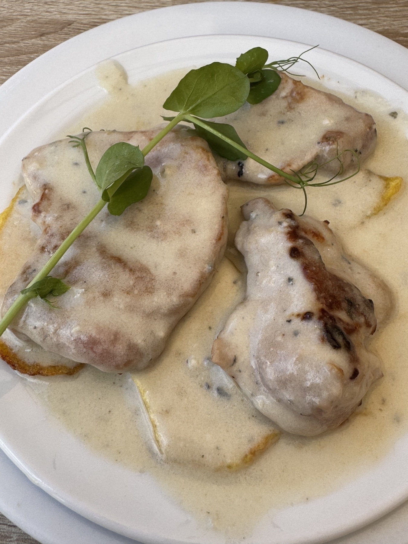 Juicy pork tenderloin medallions bathed in a velvety Cabrales blue cheese sauce, garnished with microgreens and served over golden slices of potato, creating a creamy, hearty, and satisfying dish.
