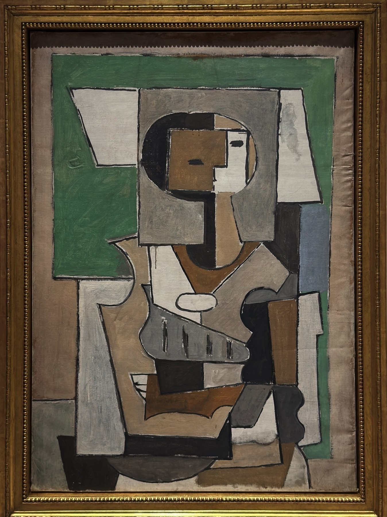 A stylized female figure rendered in muted earth tones and angular Cubist forms. The figure’s torso and face are constructed through overlapping geometric planes, a technique emblematic of Picasso’s Analytic Cubism phase. The abstraction emphasizes structural relationships over realism, turning the human figure into a visual architecture of form and color.